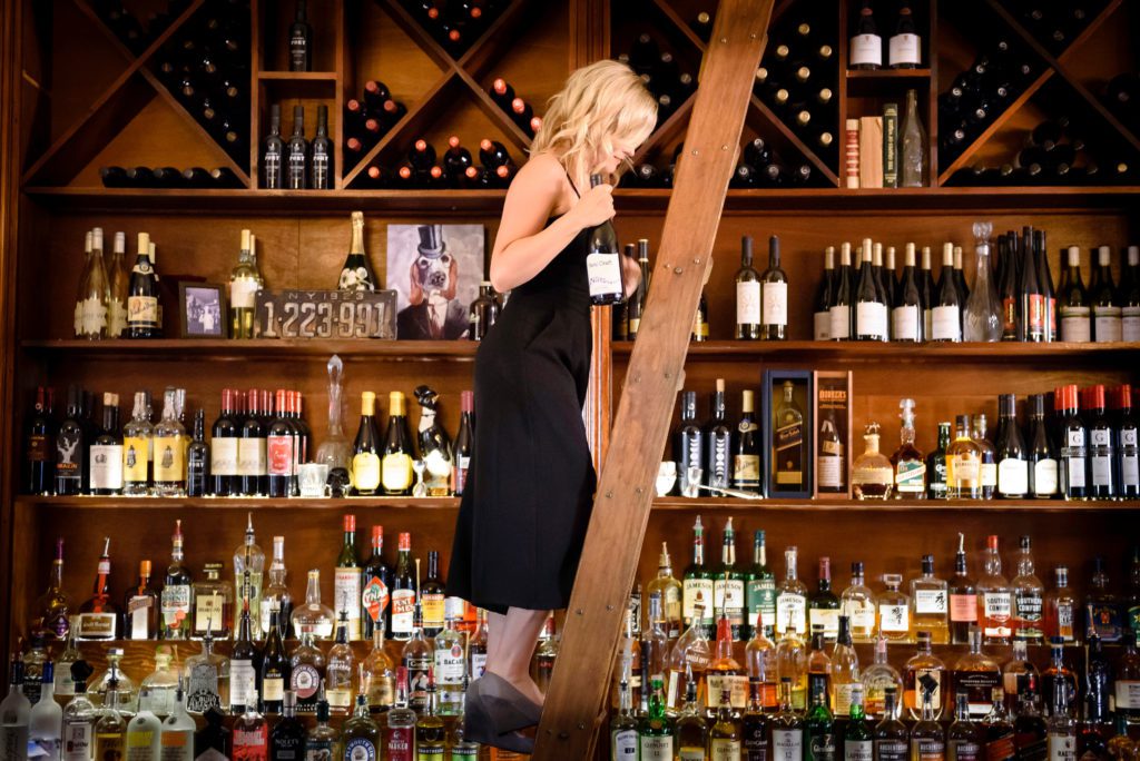 Woman retrieving liquor bottle at bar