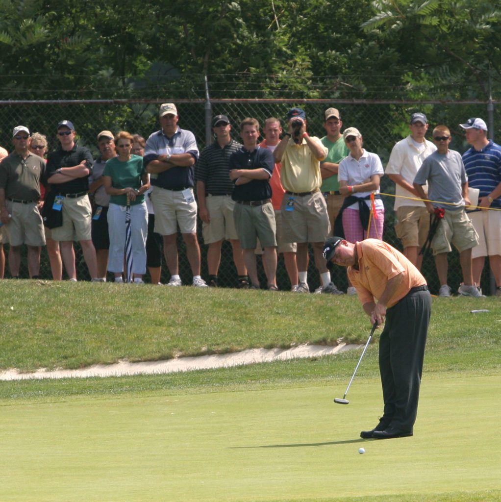 A golfer putting at the DICK'S Sporting Goods Open as a crowd watches.