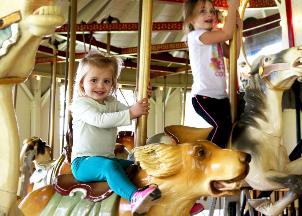 Two children riding on a carousel.