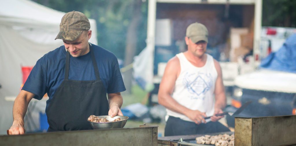 Two cooks making spiedies at outdoor event