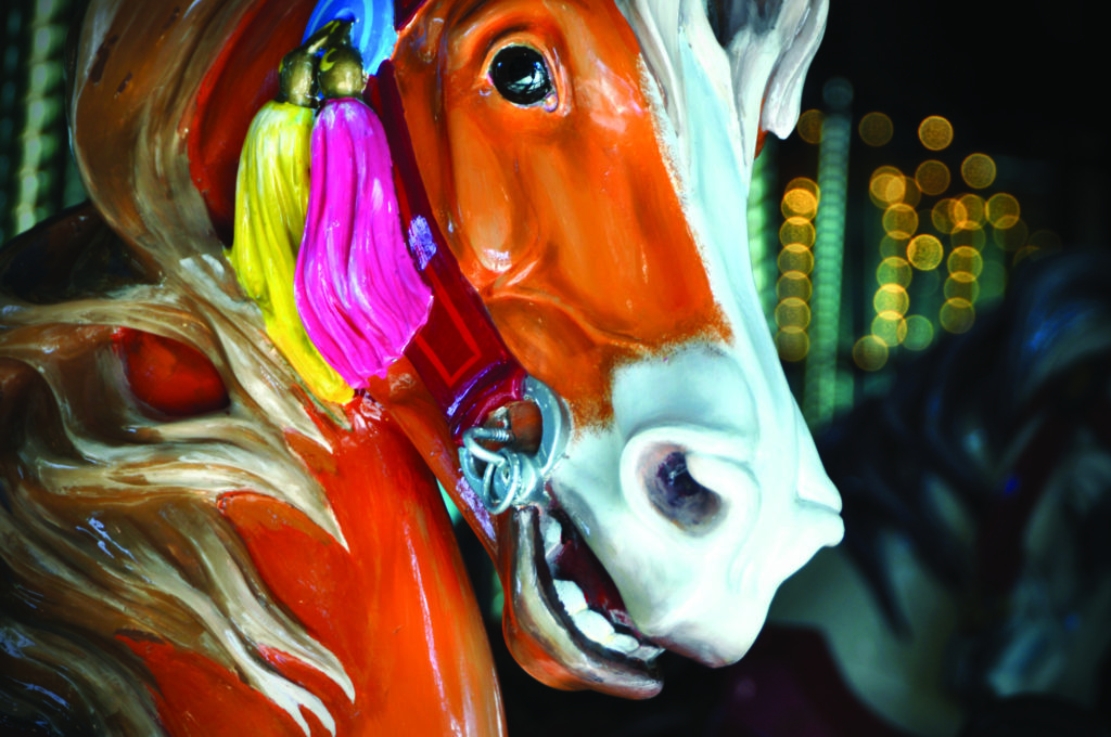Closeup of a colorful carousel horse's face.
