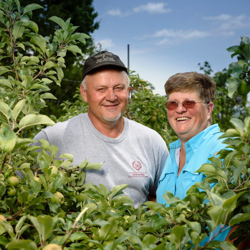 Man and woman smiling in apple orchard