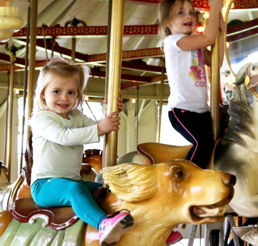 Two little girls riding a carousel.